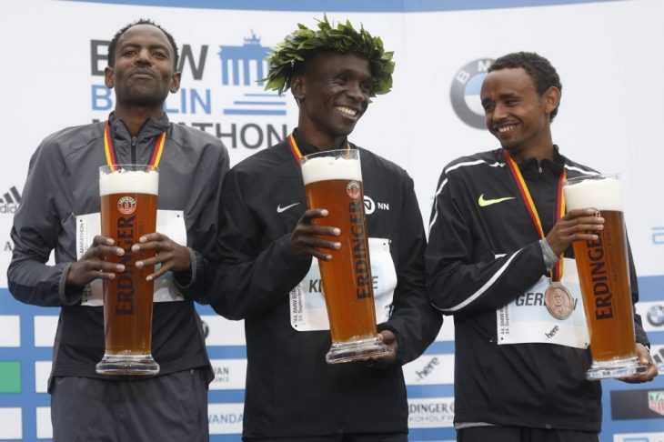 Winner Eliud Kipchoge of Kenya (C), second palced Ethiopian Guye Adola (L) and tird placed Ethiopian Mosinet Geremew celebrate with beer on the podium after the Berlin Marathon on September 24, 2017 in Berlin. / AFP PHOTO / MICHELE TANTUSSI